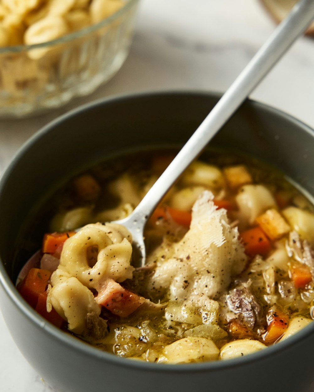 una ciotola di zuppa di pasta con dentro un cucchiaio