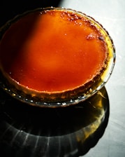 A close-up of a creamy flan napolitano topped with caramel, glowing warmly under soft natural light.