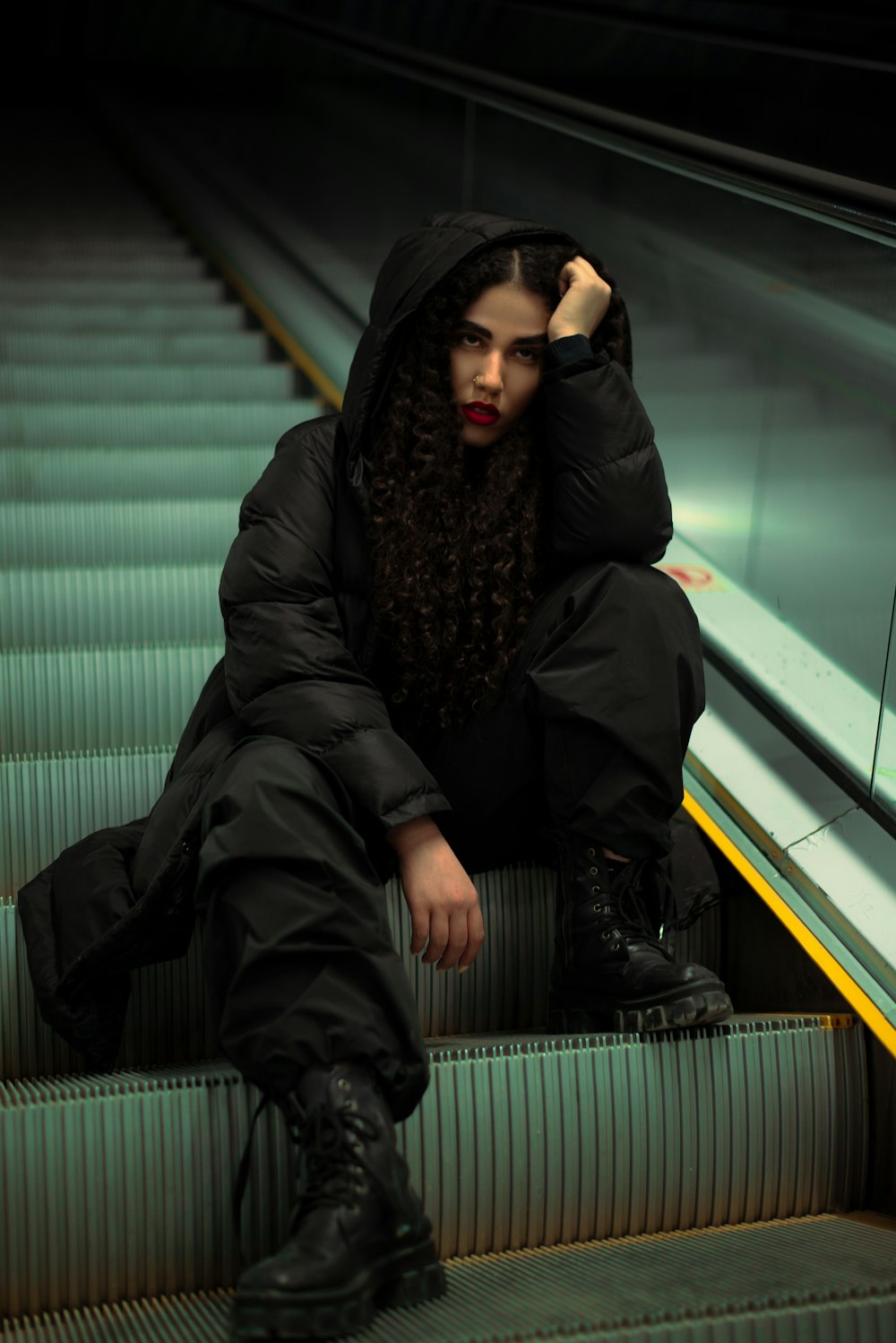 a woman sitting on an escalator with her hand on her head