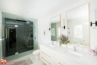 a bathroom with two sinks, a toilet and a shower