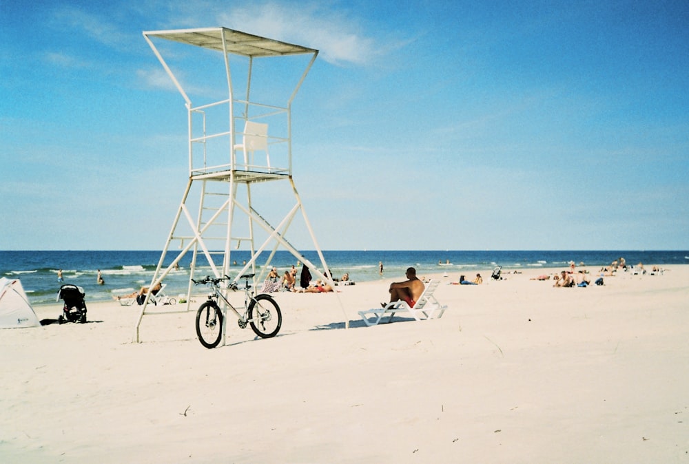a bicycle parked on a beach next to a life guard tower