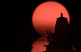 a silhouette of a building with a red sun in the background