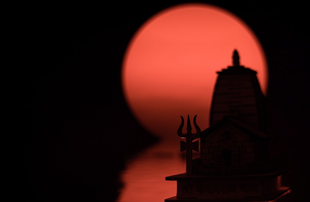 a silhouette of a building with a red sun in the background