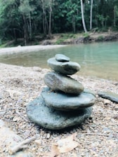 A close-up of sturdy plastic water buckets stacked neatly beside a calm riverbank.