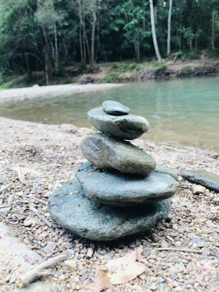 A close-up of sturdy plastic water buckets stacked neatly beside a calm riverbank.