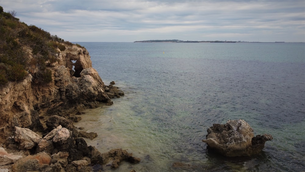 a body of water next to a rocky cliff