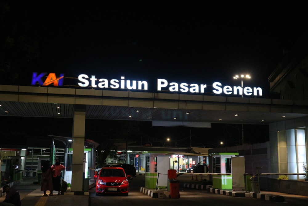 a red car is parked under a neon sign