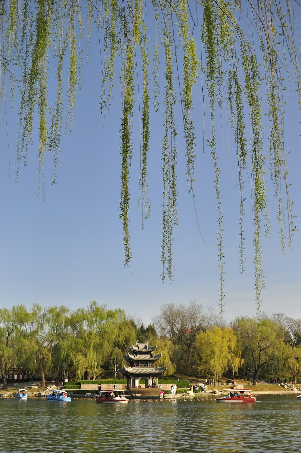 a lake with boats and a pagoda in the background