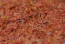 A close-up view of numerous dried saffron strands with a rich, vibrant red and orange hue.