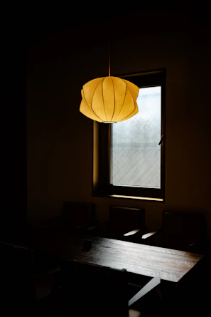 A modern pendant light casting a warm glow over a minimalist dining table.