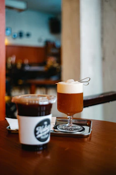 A cozy cafe table with a steaming cup of coffee and a refreshing iced drink side by side.