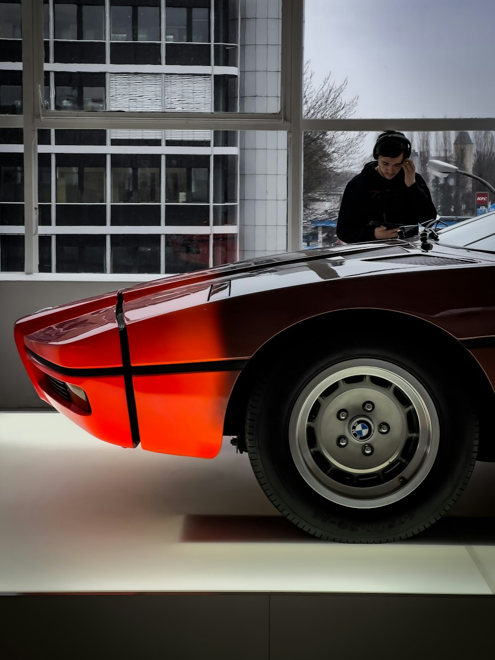 a man sitting on top of a red sports car