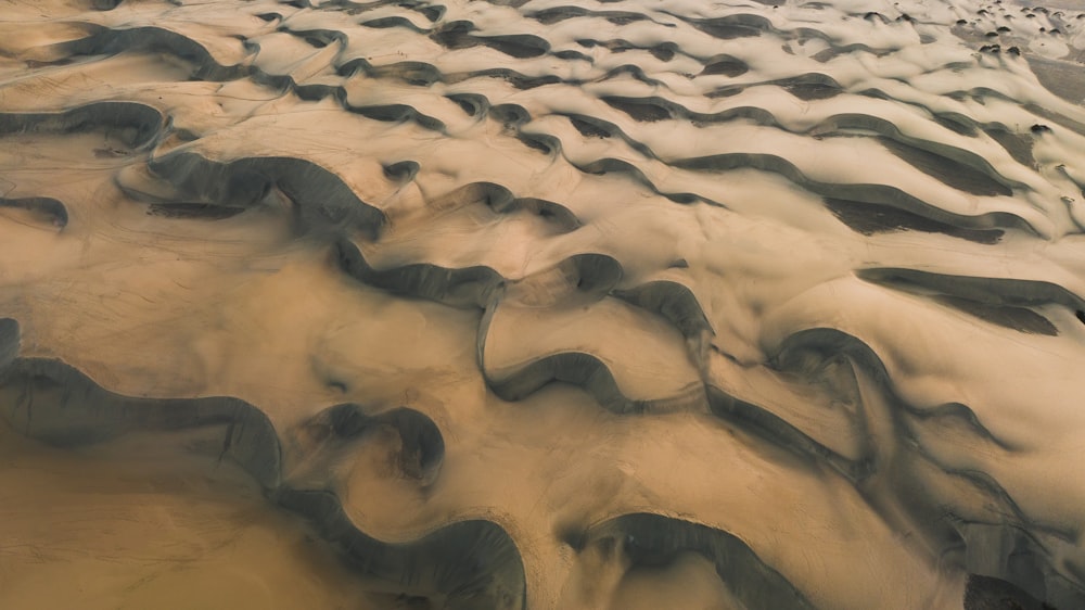 an aerial view of a sandy beach with waves in the sand