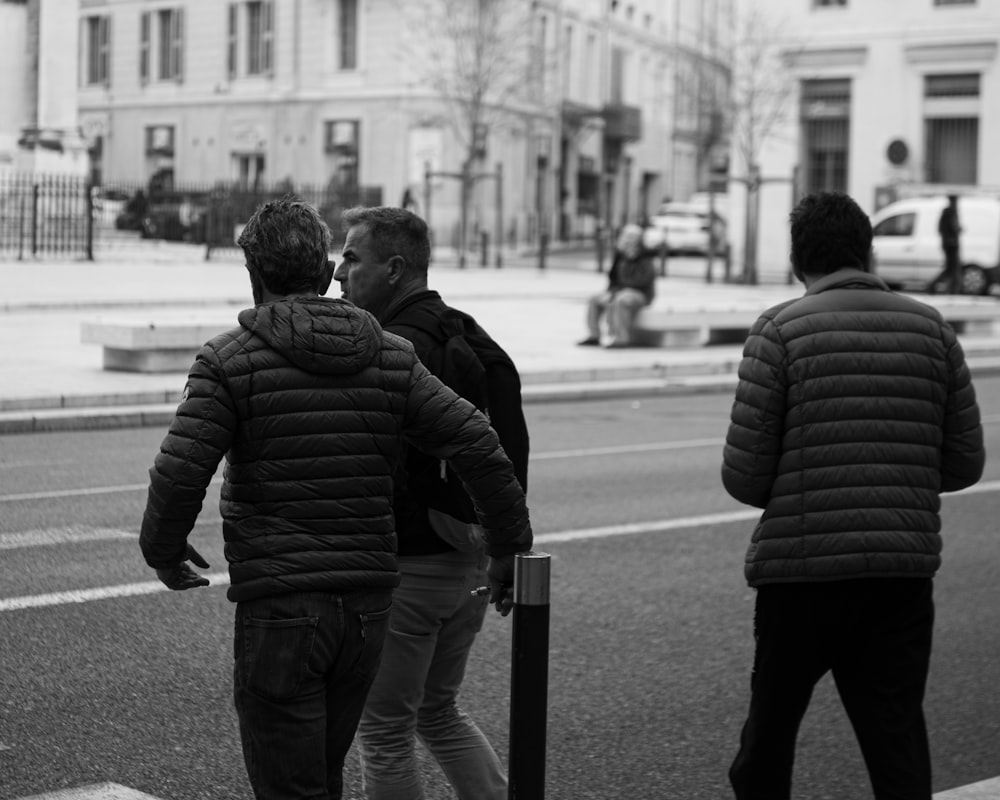 a group of men walking down a street next to a tall building