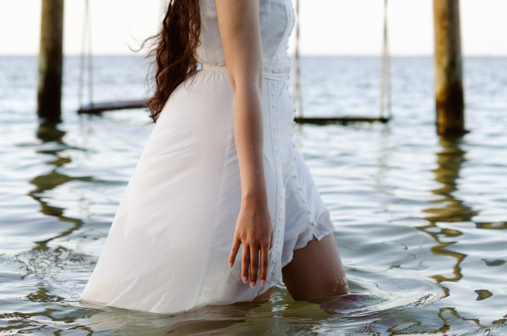 a woman in a white dress standing in the water