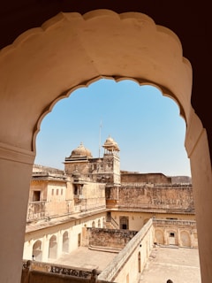 A vintage sepia-toned photograph of an ancient Indian fort with intricate stone carvings and majestic arches.