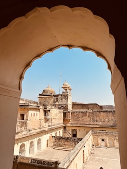 A vintage sepia-toned photograph of an ancient Indian fort with intricate stone carvings and majestic arches.