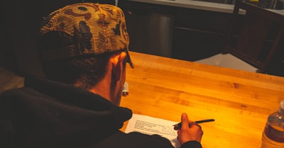 a man sitting at a table writing on a piece of paper