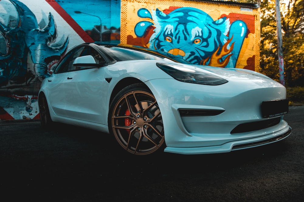 a white sports car parked in front of a graffiti covered wall