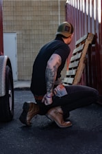 a man sitting on the ground next to a wooden bench