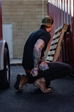 a man sitting on the ground next to a wooden bench
