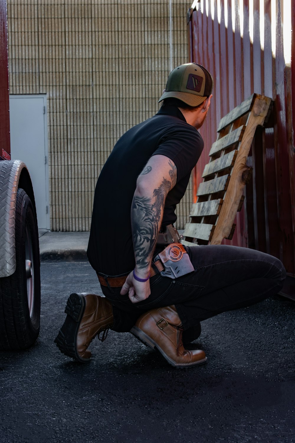 a man sitting on the ground next to a wooden bench