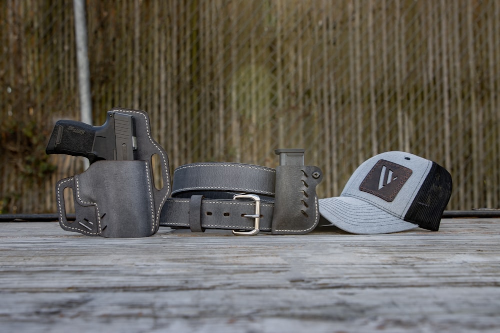 a hat, belt, and other items sit on a wooden surface