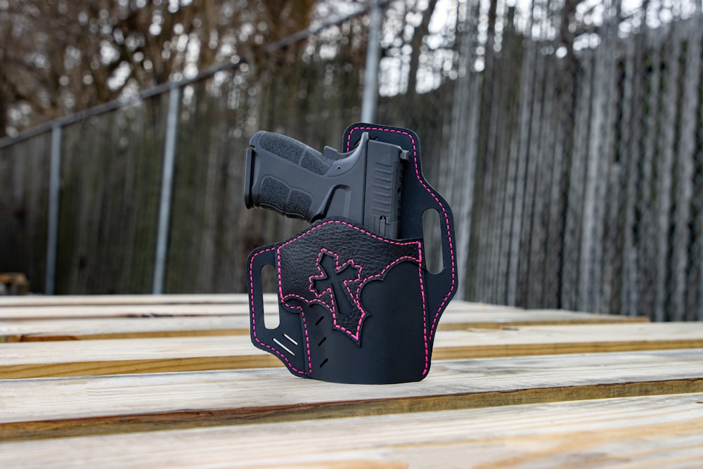 a black holster with pink stitching on it