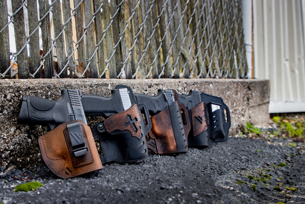 a row of holsters on the ground behind a chain link fence