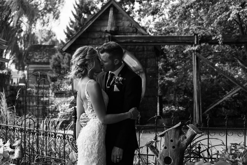 a bride and groom standing in front of a fence