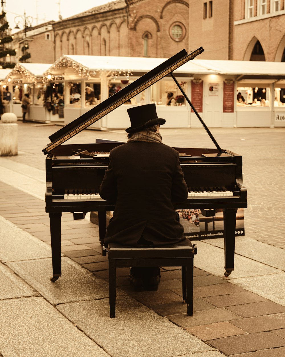 a man sitting at a piano on a sidewalk