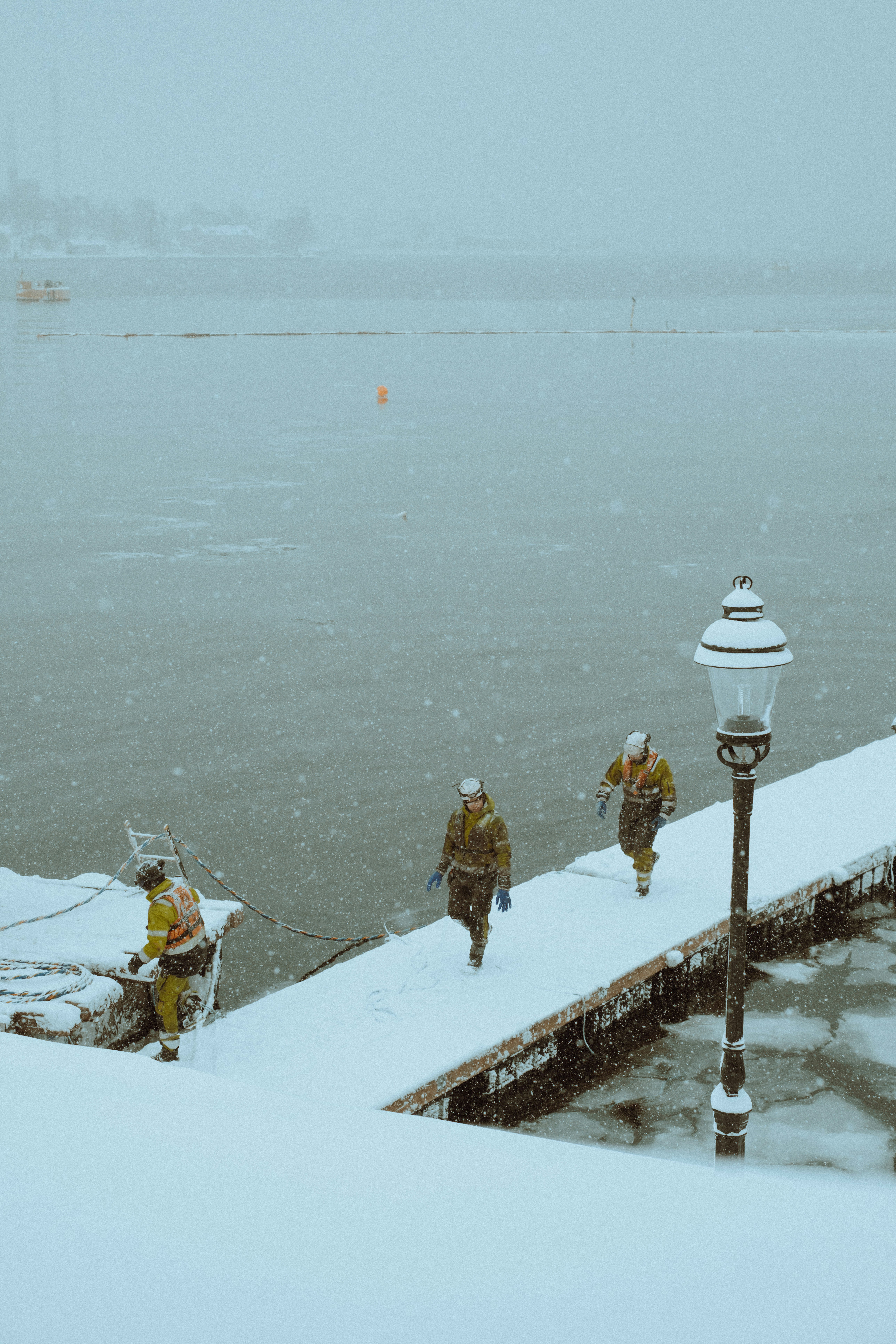 a group of people walking across a snow covered pier