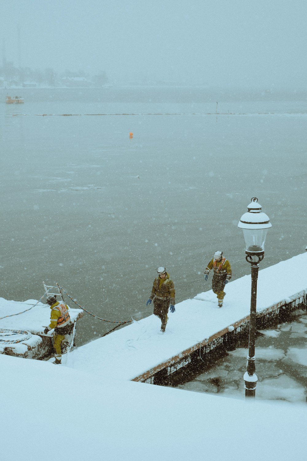 a group of people walking across a snow covered pier