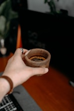 a person holding a wooden bowl over a laptop