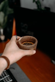 a person holding a wooden bowl over a laptop