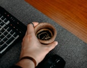 Close-up of hands typing on a keyboard with a cup of coffee nearby.