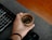 Close-up of hands typing on a keyboard with a coffee cup nearby.