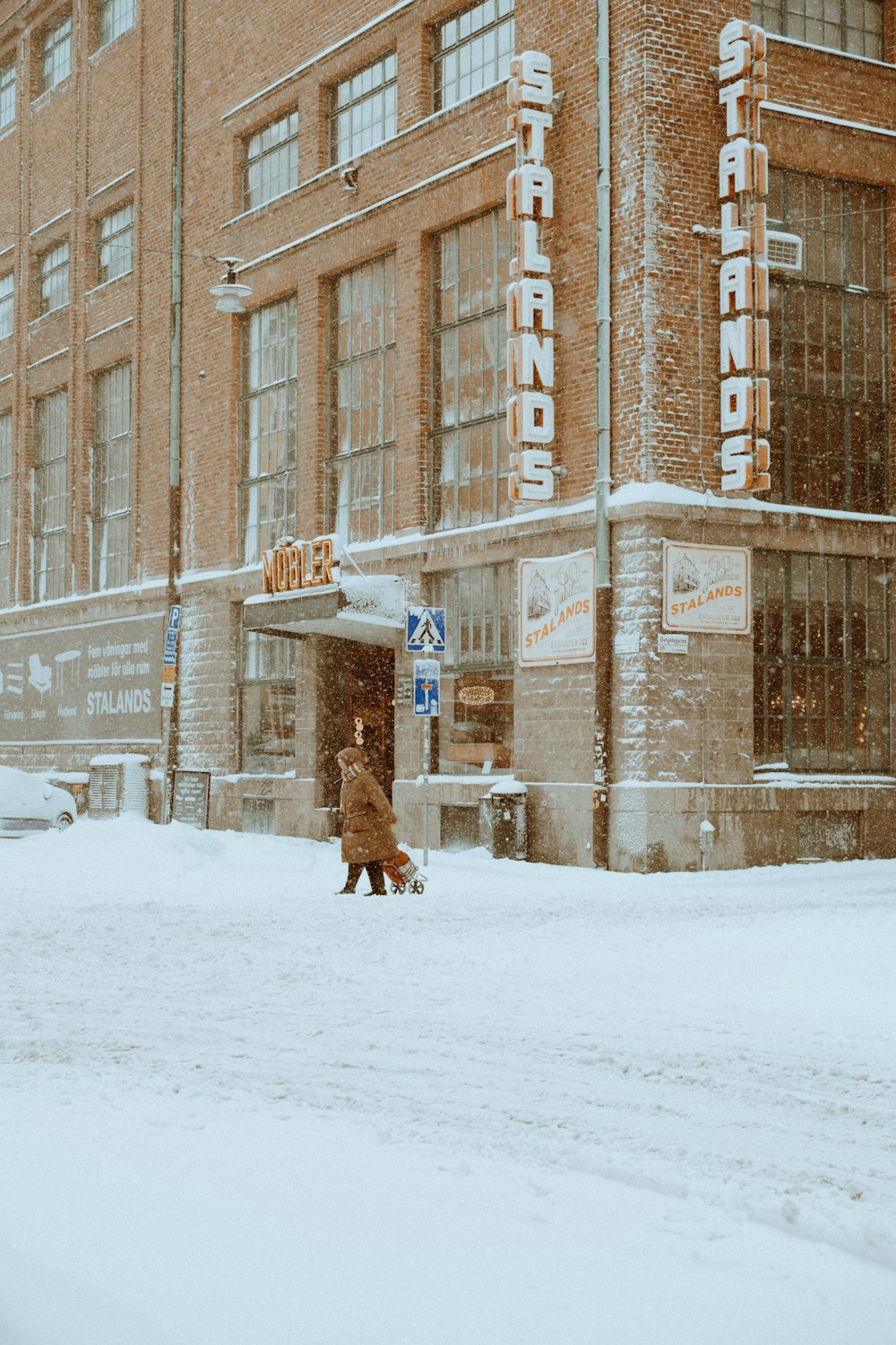 a person walking in the snow in front of a building