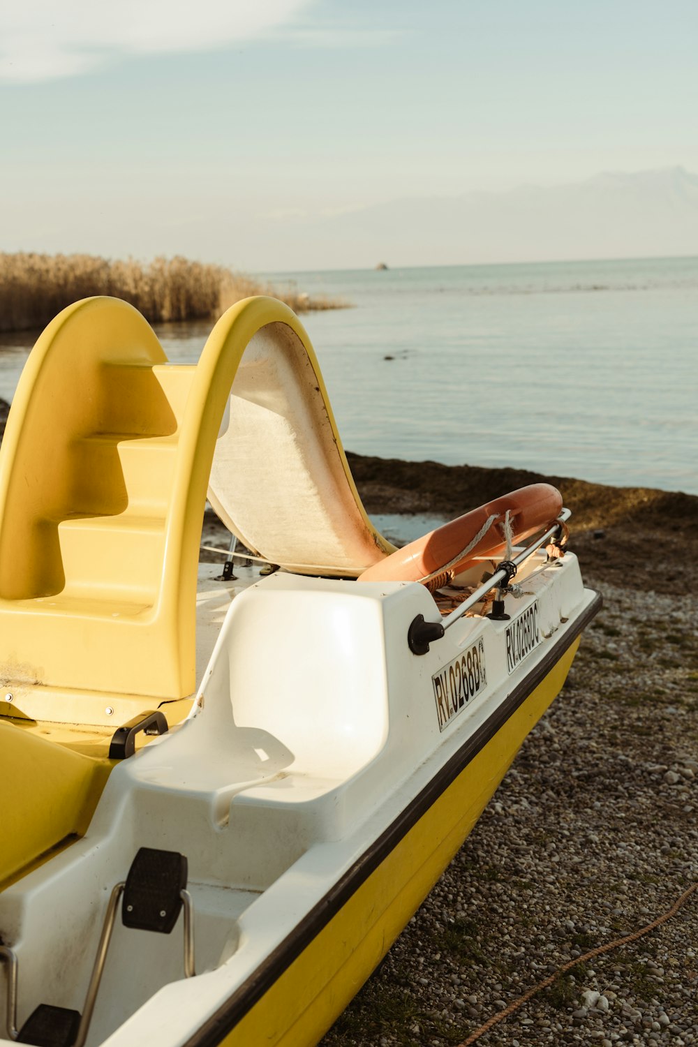 a yellow and white boat sitting on top of a beach