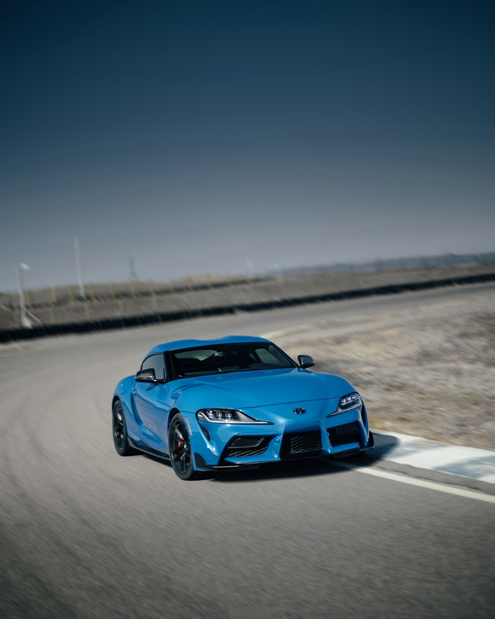 a blue sports car driving down a road