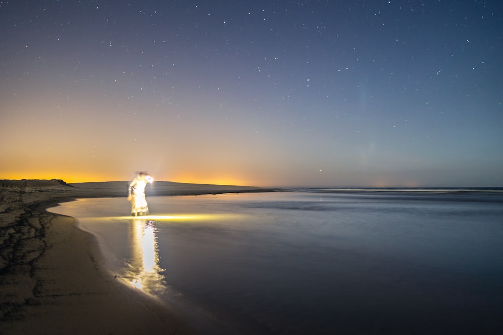 a person standing on a beach at night