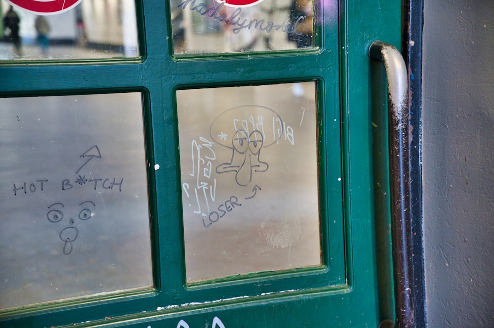 a green door with graffiti written on it