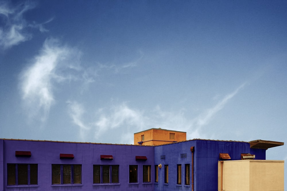 a purple building with a red roof and a blue sky