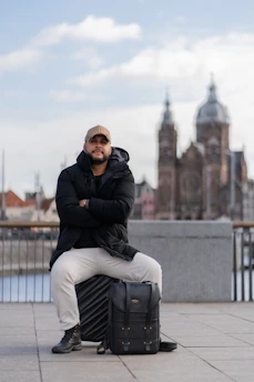 a man sitting on top of a piece of luggage