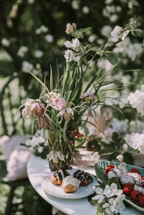 A vibrant grazing table set outdoors with fresh fruits, cheeses, and flowers under soft natural light.