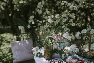 A delicate arrangement of fresh flowers paired with chocolate-covered strawberries on a minimalist white table.