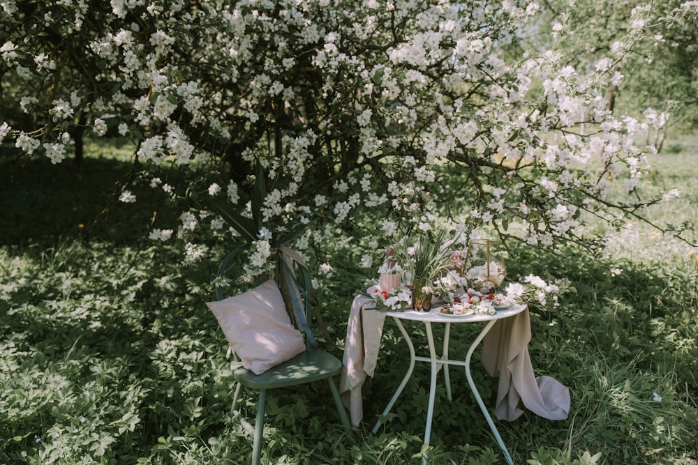 a table and two chairs under a flowering tree