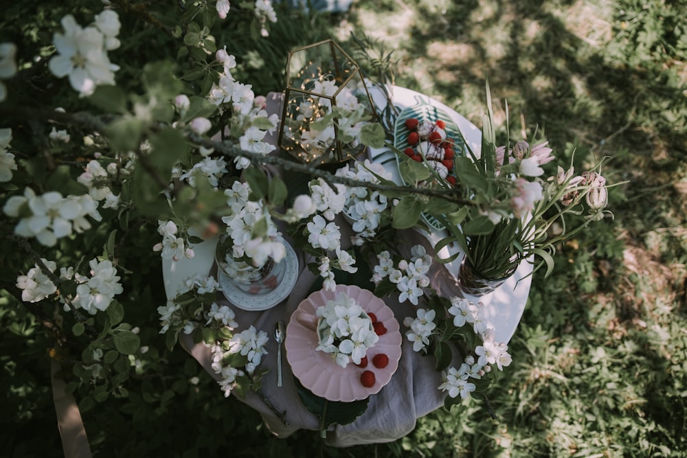 a table topped with plates and flowers on top of a lush green field