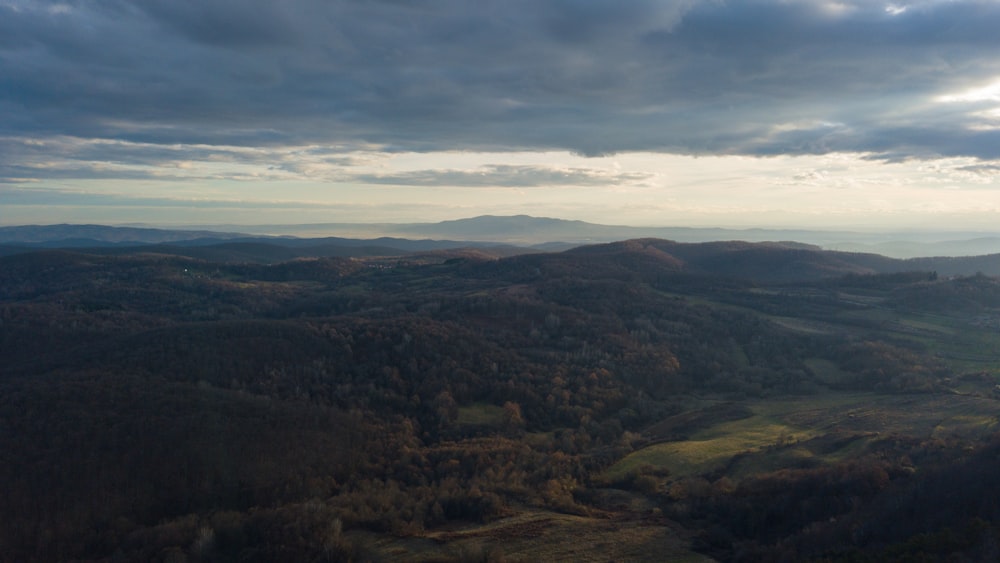 a scenic view of a valley and mountains under a cloudy sky