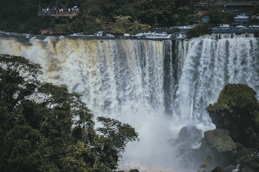 a large waterfall with people standing on the side of it